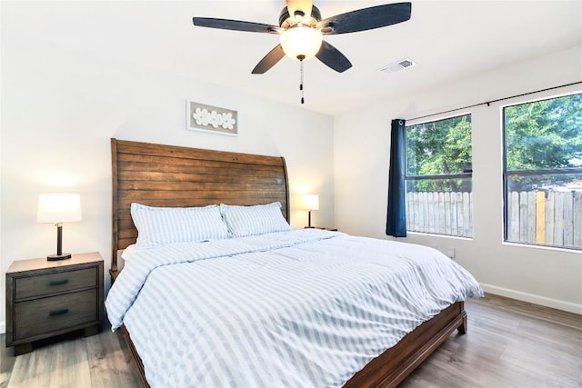 bedroom with ceiling fan, baseboards, visible vents, and wood finished floors