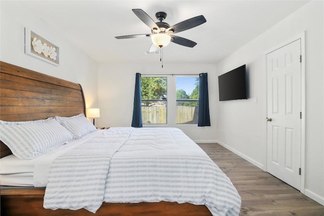 bedroom featuring baseboards, ceiling fan, wood finished floors, and visible vents