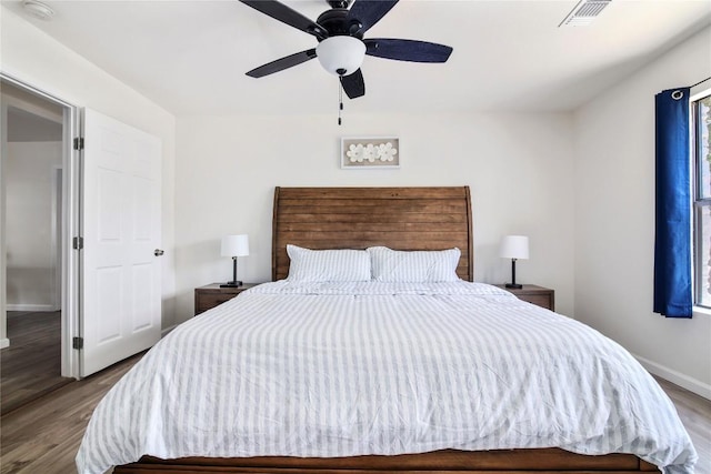 bedroom featuring ceiling fan, wood finished floors, visible vents, and baseboards