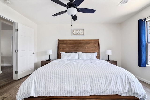 bedroom featuring visible vents, a ceiling fan, baseboards, and wood finished floors