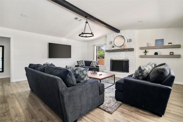 living area with vaulted ceiling with beams, a stone fireplace, wood finished floors, and visible vents