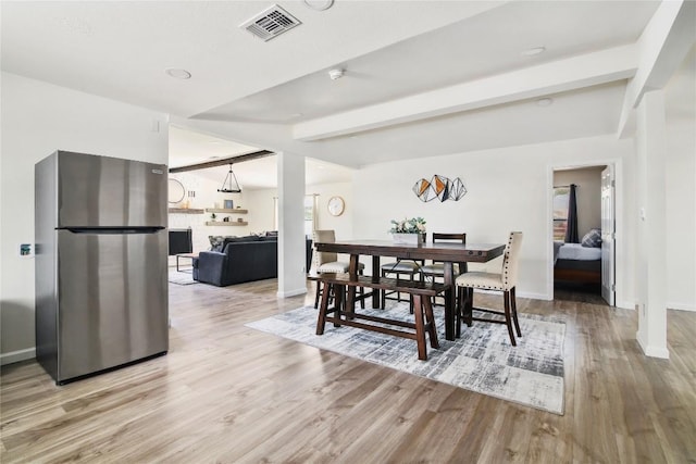 dining space featuring baseboards, beamed ceiling, light wood-style flooring, and visible vents