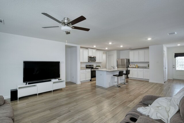 13029 Field Plow Ln, Elgin, TX 78621 - living room featuring light wood-type flooring, ceiling fan, recessed lighting, baseboards, and a textured ceiling