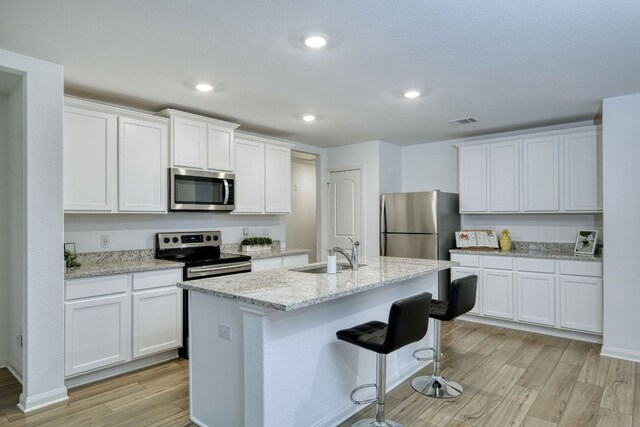 13029 Field Plow Ln, Elgin, TX 78621 - kitchen featuring stainless steel appliances, a sink, light wood-style floors, white cabinets, and recessed lighting