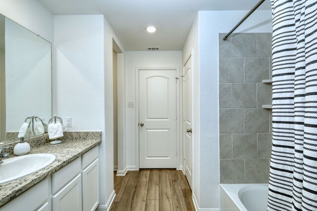 13029 Field Plow Ln, Elgin, TX 78621 - full bathroom featuring wood finished floors, vanity, shower / bath combination with curtain, and baseboards