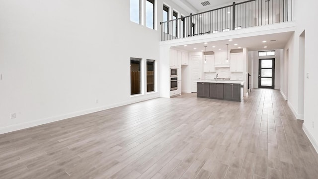 702 Bay Breeze Dr, Kyle, TX 78640 - unfurnished living room featuring light wood-style floors and a towering ceiling