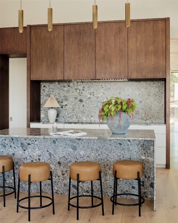 kitchen featuring light wood-style flooring, modern cabinets, decorative backsplash, and decorative light fixtures