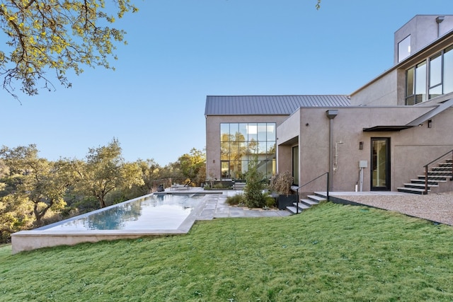 rear view of house featuring a lawn and stucco siding