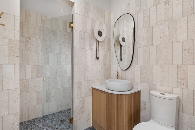 bathroom featuring toilet, a shower stall, vanity, and tile walls