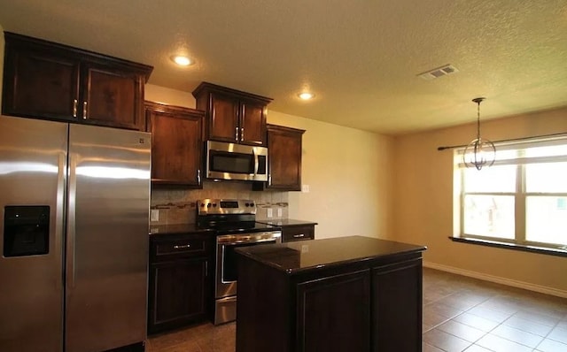 503 W Gemini Ln, Killeen, TX 76542 - kitchen featuring appliances with stainless steel finishes, dark countertops, decorative backsplash, tile patterned floors, and a kitchen island