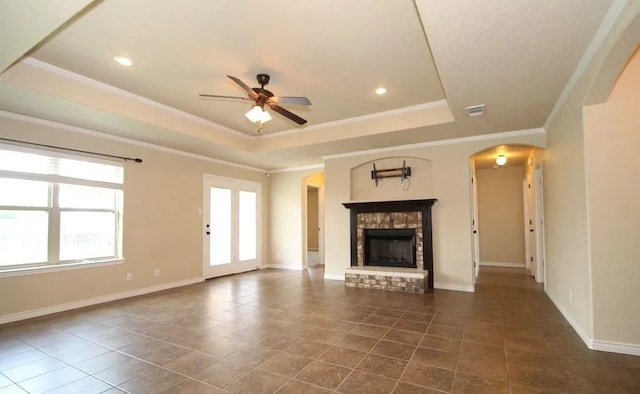 503 W Gemini Ln, Killeen, TX 76542 - unfurnished living room featuring arched walkways, ceiling fan, a raised ceiling, dark tile patterned floors, and a fireplace