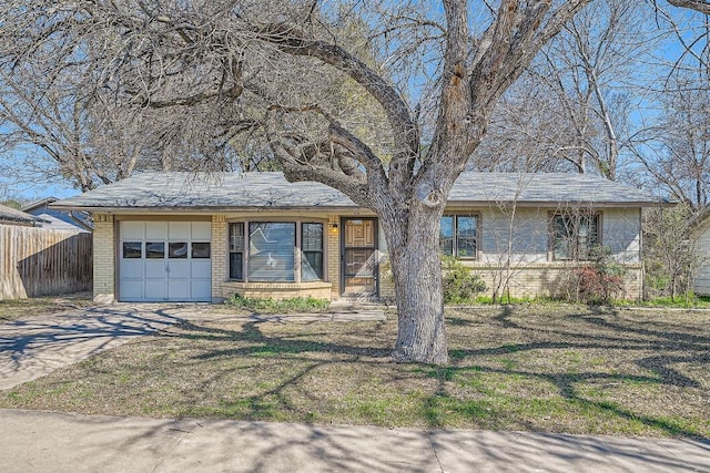 view of front facade with an attached garage, brick siding, fence, driveway, and a front lawn