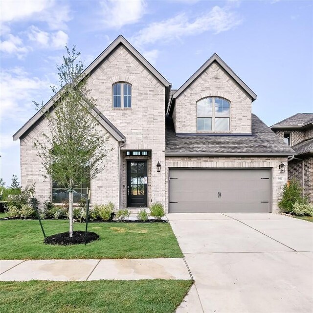 657 Bay Breeze Dr, Kyle, TX 78640 - french country inspired facade with brick siding, concrete driveway, a front lawn, and an attached garage