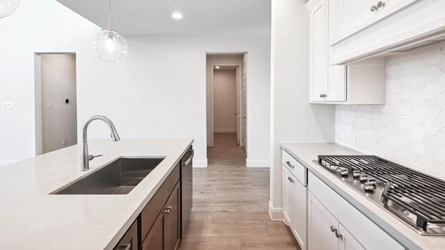 657 Bay Breeze Dr, Kyle, TX 78640 - kitchen with stainless steel gas cooktop, light countertops, backsplash, pendant lighting, and light wood-type flooring