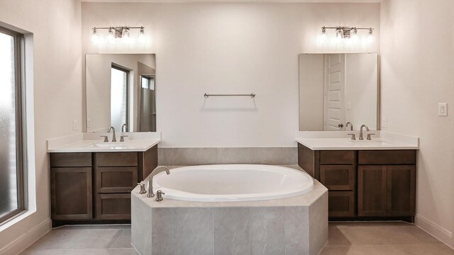 657 Bay Breeze Dr, Kyle, TX 78640 - bathroom featuring a bath, two vanities, tile patterned floors, and healthy amount of natural light