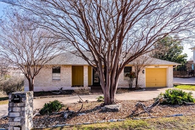 single story home featuring stone siding, roof with shingles, an attached garage, and driveway