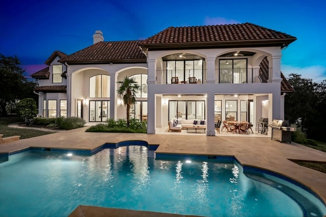 rear view of house featuring a patio, a chimney, stucco siding, outdoor lounge area, and a balcony