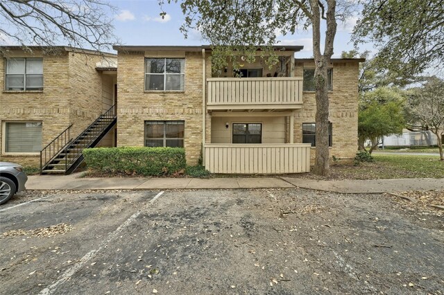 8210 Bent Tree Rd Unit 115, Austin, TX 78759 - view of front of home with a balcony, uncovered parking, brick siding, and stairs