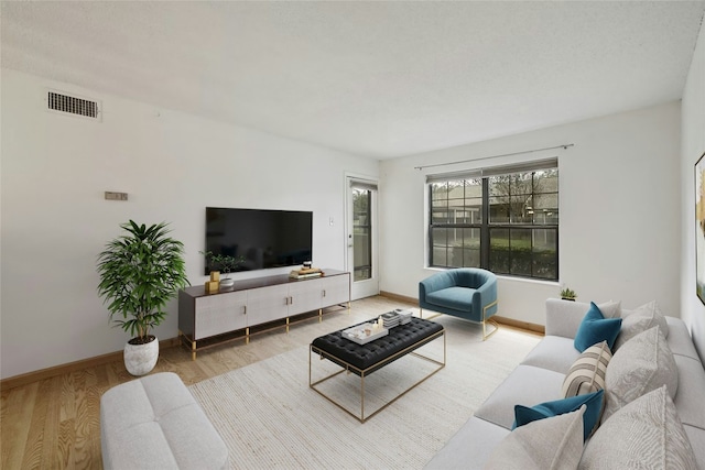 living area with visible vents, light wood-style flooring, and baseboards