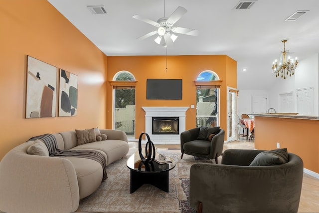 living room with vaulted ceiling, a glass covered fireplace, and visible vents