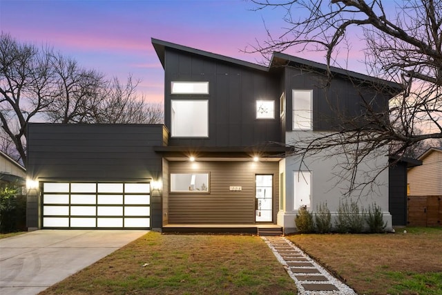 contemporary home featuring a garage, a lawn, board and batten siding, and concrete driveway