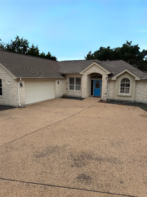 view of front of house featuring concrete driveway, a shingled roof, and an attached garage