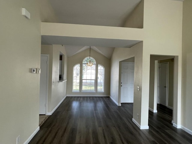 unfurnished dining area with dark wood-style floors, lofted ceiling, a notable chandelier, and baseboards