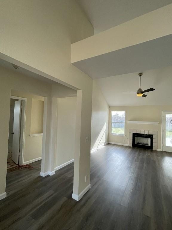 unfurnished living room featuring a tile fireplace, dark wood finished floors, ceiling fan, and baseboards