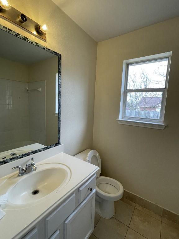 bathroom with toilet, vanity, tile patterned flooring, baseboards, and walk in shower