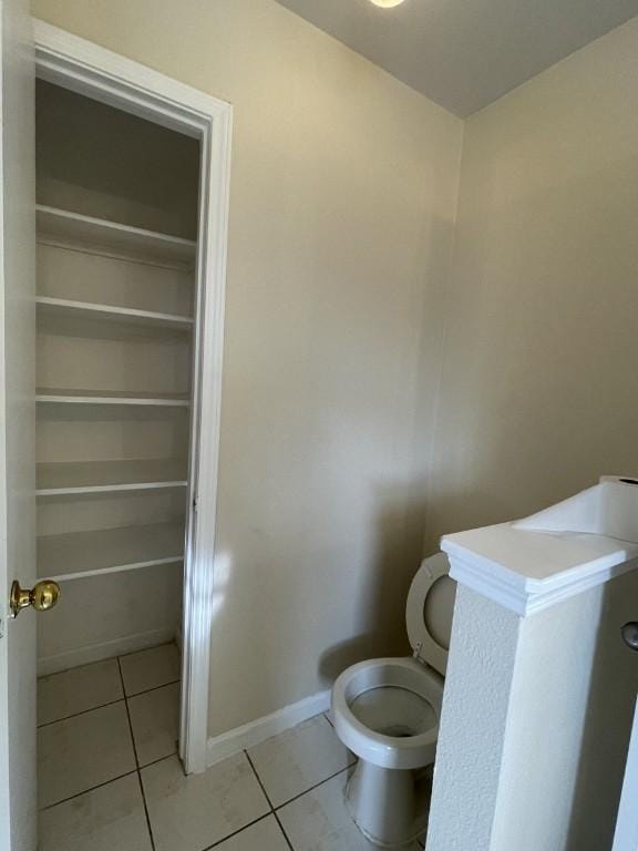 bathroom featuring tile patterned flooring, toilet, and baseboards