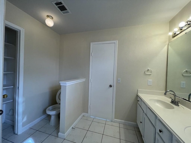 bathroom with double vanity, baseboards, visible vents, toilet, and a sink