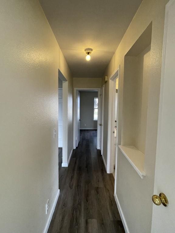 hallway with dark wood-style floors and baseboards