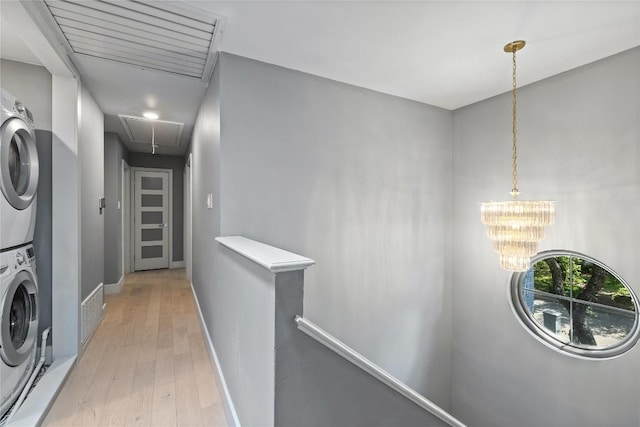 4704 Wild Briar Pass, Austin, TX 78746 - laundry area with attic access, stacked washer and clothes dryer, light wood-style floors, baseboards, and a chandelier