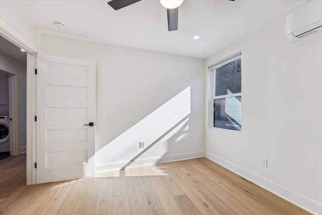 empty room with light wood finished floors, washer / clothes dryer, ceiling fan, a wall mounted air conditioner, and baseboards