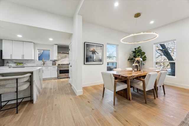 dining space with a wealth of natural light, light wood-style flooring, and baseboards