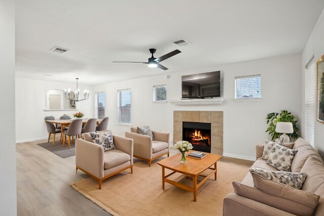 114 Challenger, Kyle, TX 78640 - living area featuring light wood-style floors, a chandelier, a tiled fireplace, baseboards, and a ceiling fan
