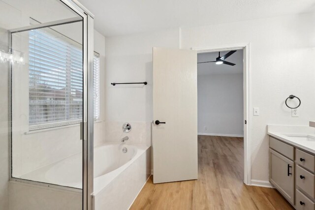 114 Challenger, Kyle, TX 78640 - bathroom with wood finished floors, a garden tub, a ceiling fan, vanity, and a stall shower
