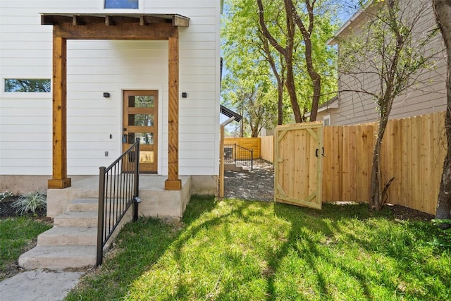 property entrance featuring fence and a lawn