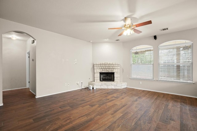 19907 Kennemer Dr, Pflugerville, TX 78660 - unfurnished living room with wood finished floors, ceiling fan, arched walkways, and a stone fireplace