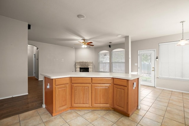 19907 Kennemer Dr, Pflugerville, TX 78660 - kitchen featuring ceiling fan, a fireplace, light countertops, arched walkways, and open floor plan