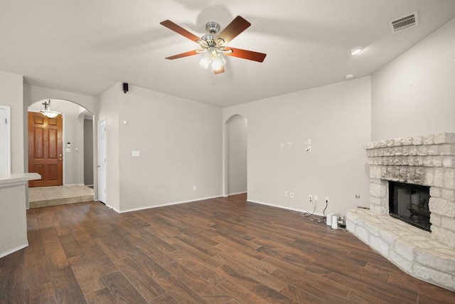 19907 Kennemer Dr, Pflugerville, TX 78660 - unfurnished living room featuring arched walkways, a stone fireplace, wood finished floors, and a ceiling fan