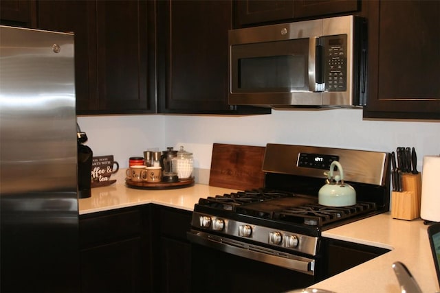 kitchen with stainless steel appliances, dark brown cabinets, and light countertops