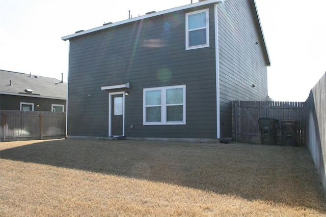 rear view of house featuring fence and a yard