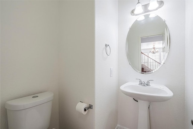 half bath with toilet and an inviting chandelier