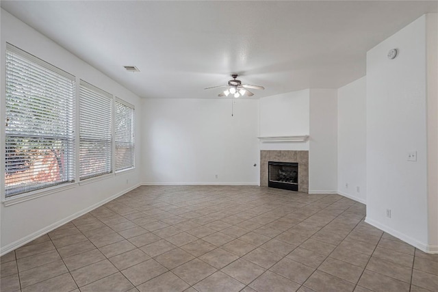 6205 York Bridge Cir, Austin, TX 78749 - unfurnished living room featuring a ceiling fan, light tile patterned flooring, a tiled fireplace, and baseboards