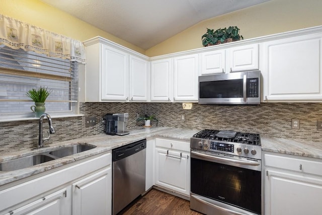 kitchen with lofted ceiling, white cabinetry, stainless steel appliances, and a sink