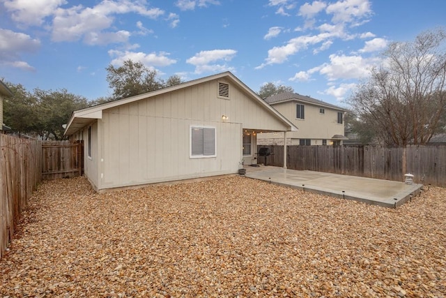 back of property with a fenced backyard and a patio