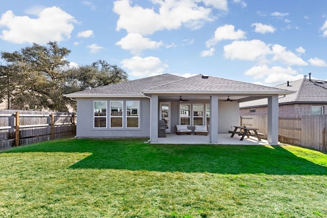rear view of house with ceiling fan, a yard, a fenced backyard, stucco siding, and a patio