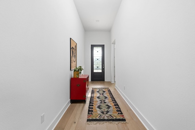 doorway to outside with light wood-type flooring and baseboards