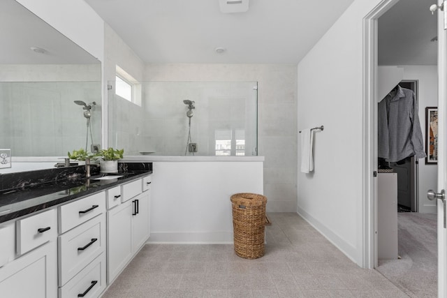 bathroom featuring a walk in shower, vanity, and baseboards